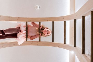 Ein Mädchen klettert im Familienhotel Tirolerhof eine Holzleiter hoch und blickt neugierig nach unten