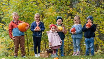 Einige Kinder halten jeweils einen Kürbis in den Armen.