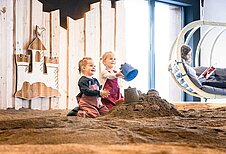 Zwei Mädchen spielen in der Indoor Sandkiste des Familienhotels Allgäuer Berghof.