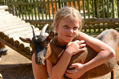 Mädchen streichelt eine Ziege im Kleintierbereich des Familienhotels Family Club Harz. Im Rahmen der Kinderbetreuung werden die lieben Tiere regelmäßig besucht.