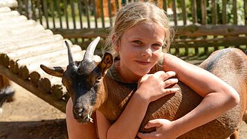 Mädchen streichelt eine Ziege im Kleintierbereich des Familienhotels Family Club Harz. Im Rahmen der Kinderbetreuung werden die lieben Tiere regelmäßig besucht.