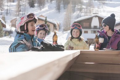 Mutter und drei Kinder in Skiausrüstung machen eine Pause