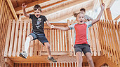 Zwei Kinder Hüpfen in der Scheune des Familienhotels Huber in Südtirol ins Heu.
