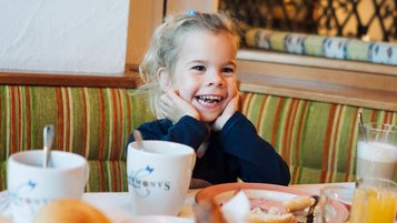 Glückliches Kind genießt das Frühstück im Familienhotel Der Kirchheimerhof in Kärnten.