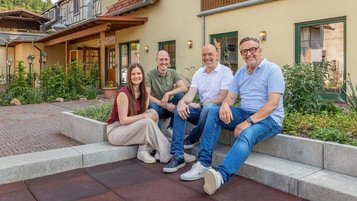Gastgeberfamilie des Familienhotel Ottonenhof im Sauerland sitzt gemeinsam vor dem Hotelgebäude.