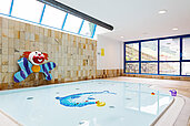 Babybecken mit Wanddeko "Clown" und großen Fenstern im Familienhotel Wellness- & Familienhotel Egger in Saalbach Hinterglemm