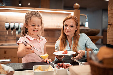 Mutter und Tochter bedienen sich am Buffet des Familienhotels Family Home Alpenhof.