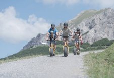 Eltern sind mit ihren Kindern auf dem Naturspielplatz und die Tochter schaukelt auf der Schaukel im Familienhotel Liechtenstein.