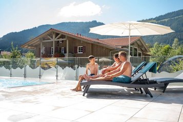 Familie entspannt gemeinsam auf den Liegen am Außenpool des Familienhotels Krone im Allgäu.