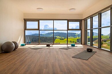 Yogaraum mit Yogamatten und einer wundervollen Aussicht auf die Landschaft durch große Panoramafenster im Familienhotel Familien Resort Petschnighof in Kärnten.