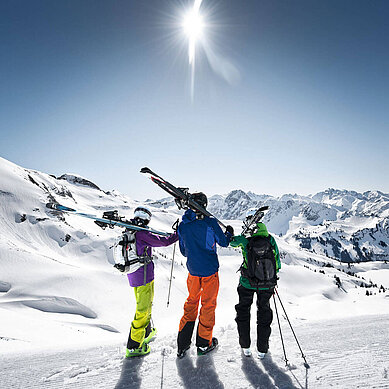 Eine Gruppe von Leuten machen Pause, halten ihre Ski und genießen die Aussicht im Winter vom Nebelhorn im Allgäu. Der Tag ist strahlend schön.