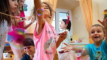 Die Kinder spielen im Happy Club mit Seifenblasen im Familienhotel Der Ponyhof Steiermark.
