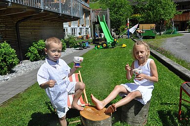 Die Kinder essen Eis auf dem Spielplatz im Familienhotel Sonne Bezau Vorarlberg.