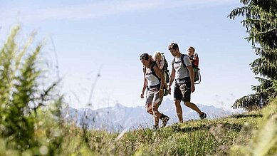 Eltern wandern mit ihren Kleinkindern auf dem Rücken durch die Allgäuer Alpen in der Nähe vom Allgäuer Berghof.