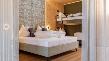 Familienzimmer im Familienhotel Almfamilyhotel Scherer mit Doppelbett und Stockbett aus Holz für Eltern und Kinder.