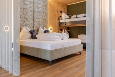 Familienzimmer im Familienhotel Almfamilyhotel Scherer mit Doppelbett und Stockbett aus Holz für Eltern und Kinder.