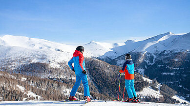 Zwei Kinder stehen auf Skiern auf der Skipiste in Kärnten.