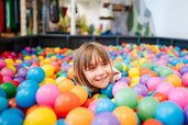 Kind spielt fröhlich im bunten Bällebad des Familien Resort Petschnighof in Kärnten.