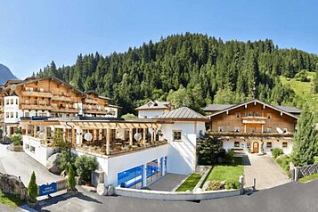 Außenansicht des Habachklause Familien Bauernhof Resort im Salzburger Land, umgeben grünen Wäldern im Sommer.
