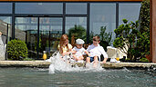 Drei Kinder sitzen am Beckenrand des Pools des Familienhotels Ulrichshof und lassen ihre Füße ins Wasser hängen.
