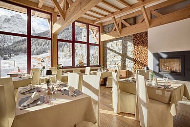 Gedeckter Tisch im Restaurant mit Panorama-Blick auf die Winterlandschaft im Familienhotel Bella Vista in Südtirol.
