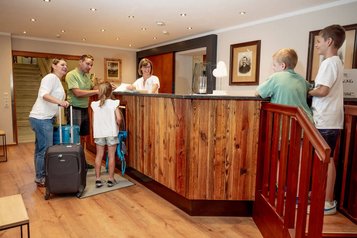 Familie wird herzlich an der Rezeption des Familienhotels Krone im Allgäu empfangen.