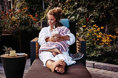 Mutter und Kind kuscheln gemeinsam auf einer Ruheliege am Außenpool des Familienhotels Landhaus Averbeck in der Lüneburger Heide.