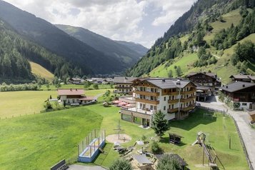 Das Familienhotel Oberkarteis im Salzburger Land ist aus der Vogelperspektive mit der umliegenden Wiese und Berglandschaft zu sehen.