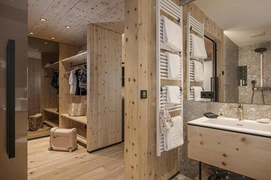 Helles Badezimmer mit Waschbecken, Handtüchern und viel Holz in einer Suite im Familienhotel Mia Alpina in Tirol.
