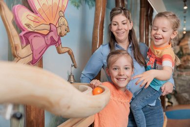 Mutter mit zwei Kindern spielt begeistert an der Murmelbahn im Familienhotel Kaiserhof.