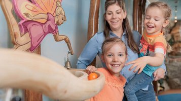 Mutter mit zwei Kindern spielt begeistert an der Murmelbahn im Familienhotel Kaiserhof.