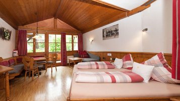 Gemütliches Familienzimmer mit Doppelbett, Sitzecke und viel Holz im Familienhotel Krone im Allgäu.