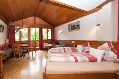 Gemütliches Familienzimmer mit Doppelbett, Sitzecke und viel Holz im Familienhotel Krone im Allgäu.