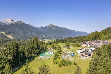 Weitläufige Hotelanlage des Familienhotels Ramsi mit Spielplatz, Sportbereich und herrlichem Bergpanorama in Kärnten.