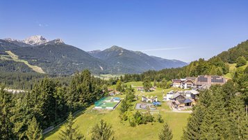 Weitläufige Hotelanlage des Familienhotels Ramsi mit Spielplatz, Sportbereich und herrlichem Bergpanorama in Kärnten.
