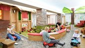 Kinder fahren mit Bobbycars durch den fantasievollen Indoor-Spielbereich mit Themenhäusern und Baustein-Areal im Familienhotel Rhön Feeling.