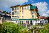 Außenansicht des Hotel Engel im Schwarzwald mit gelber Fassade, Balkonen und Gartenanlage mit Teich