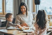 Familie genießt ein gemeinsames Frühstück im Restaurant des Familienhotels Amiamo mit frischen Brötchen und gemütlicher Atmosphäre.