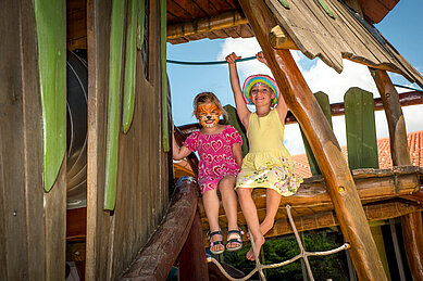 Zwei Kinder haben sich im Happy-Club Ihr Gesicht anmalen lassen und spielen nun auf dem tollen Spielplatz im Familienhotel Spa- & Familien-Resort Krone in den Allgäuer Alpen.