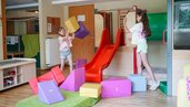 Zwei Kinder spielen mit bunten Schaumstoffbausteinen im Happy Club des Familienhotel Sonne Bezau.