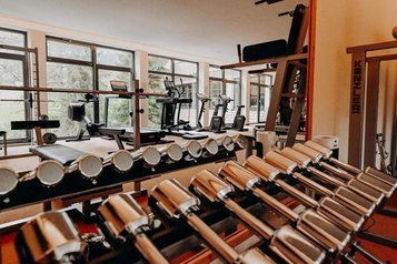 Hanteln und Trainingsgeräte stehen im Fitnessraum des Hotel Sonngastein im Salzburger Land bereit.