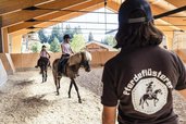 Reitunterricht in der überdachten Reithalle des Familienhotels Allgäuer Berghof im Allgäu.