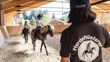 Reitunterricht in der überdachten Reithalle des Familienhotels Allgäuer Berghof im Allgäu.