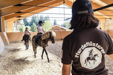 Reitunterricht in der überdachten Reithalle des Familienhotels Allgäuer Berghof im Allgäu.