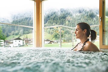 Eine Frau sitzt im Whirlpool im Alpenhotel Kindl in Tirol