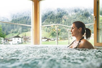 Eine Frau sitzt im Whirlpool im Alpenhotel Kindl in Tirol