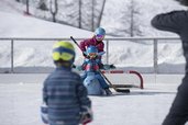 Kinder üben auf einem Eisplatz in Liechtenstein mit Lernhilfe das Eislaufen.
