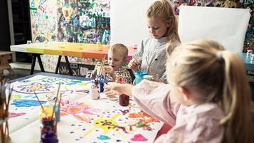 Kinder malen bunte Bilder am Maltisch in der Kinderbetreuung im Familienhotel