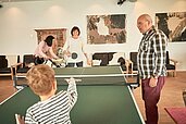 Kinder spielen zusammen mit der Familie Tischtennis im Familienhotel Amiamo im Salzburger Land.