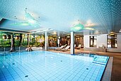 Schwimmbad mit direktem Blick auf das Kinderbecken und Liegen zum Entspannen im Familienhotel Das Bayrischzell in Oberbayern.